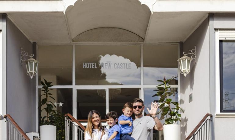 Lächelnde Familie vor einem Hotel, warme und glückliche Atmosphäre.