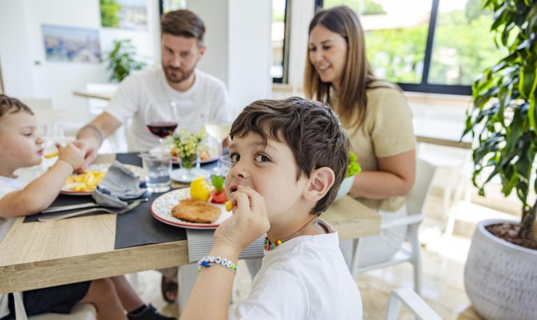 Glückliche Familie isst zusammen, lächelnde Kinder, helle und gemütliche Atmosphäre.